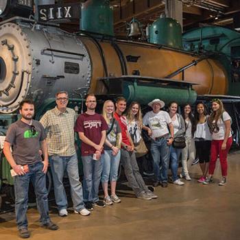 Students and faculty standing in front of a locamotive
